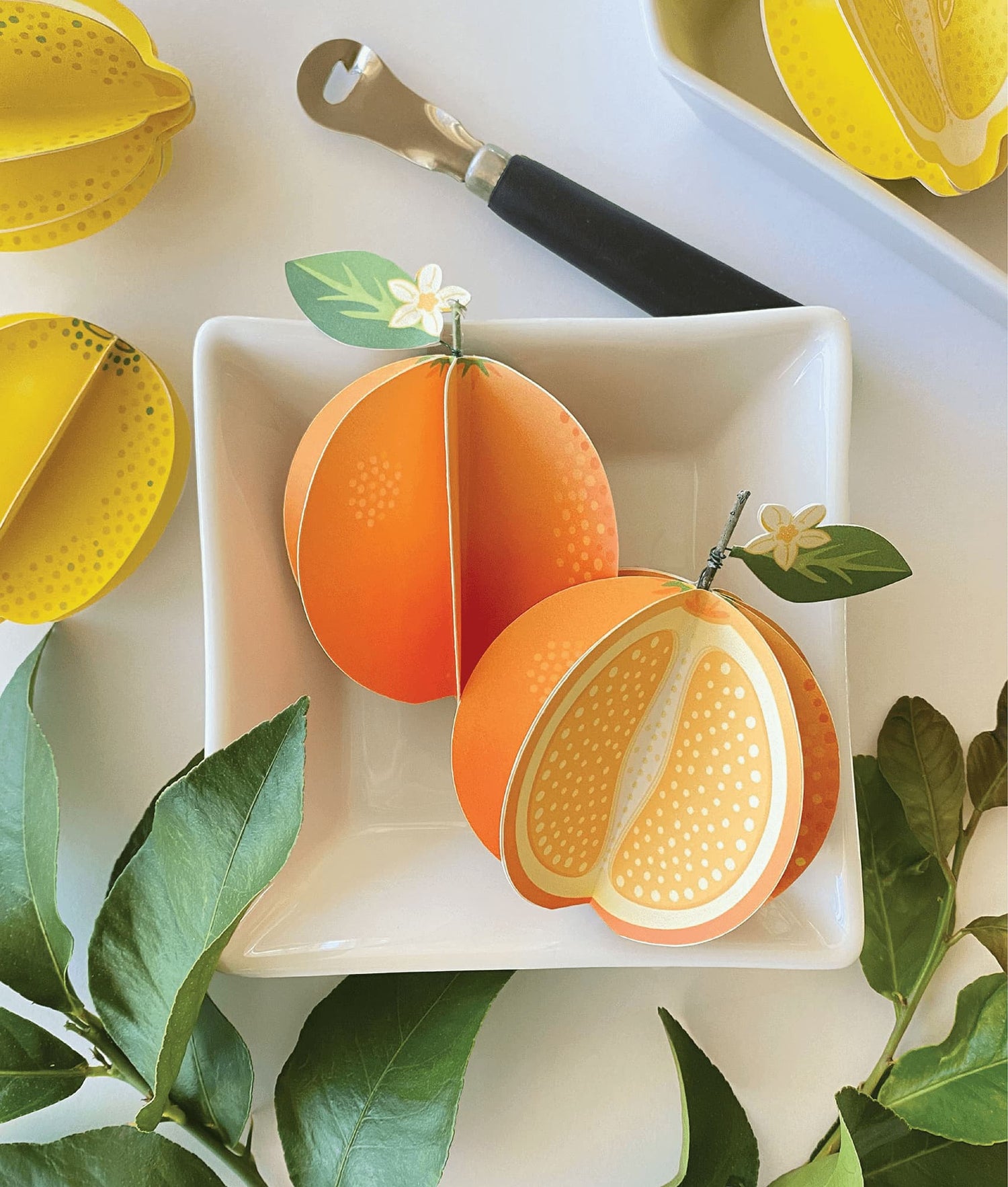 image of two paper oranges in a square bowl