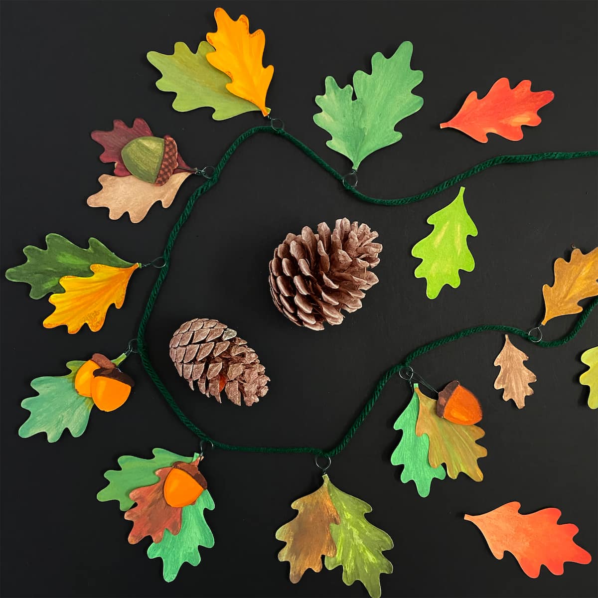 Inspirational DIY acorn and leaf garland hanging with fall colors, created with Cakewalk DIY Paper Craft templates.
