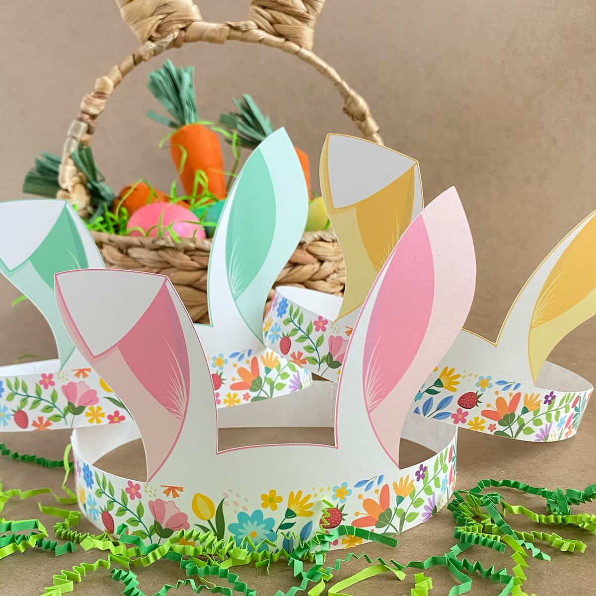 Group of three floral Easter bunny crowns in pastel yellow, pink, green with Easter props