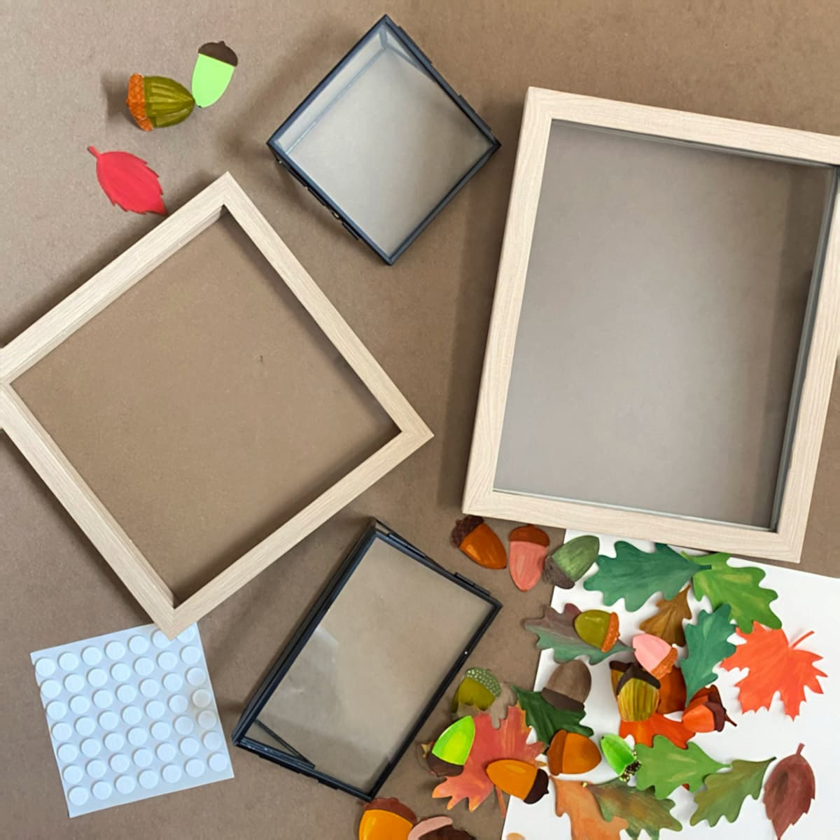 Assorted craft materials including wooden photo frames, leaf decorations, and paper acorns on a Kraft paper background for Cakewalk DIY Paper Craft tutorial.