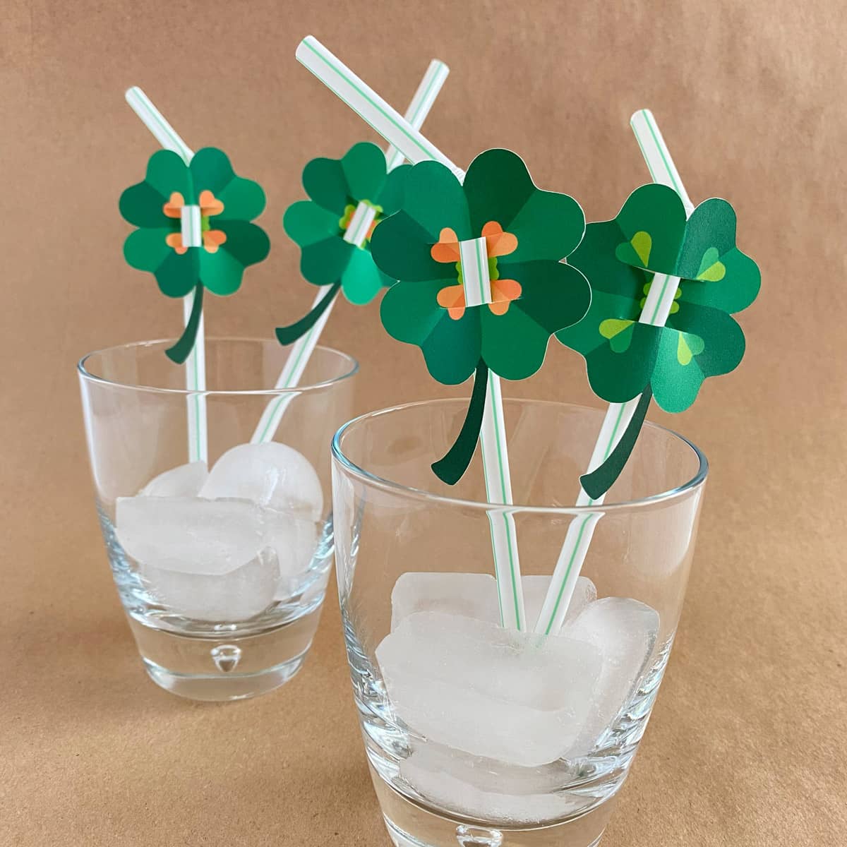 Paper shamrocks used with  straws in glasses with ice on a brown background