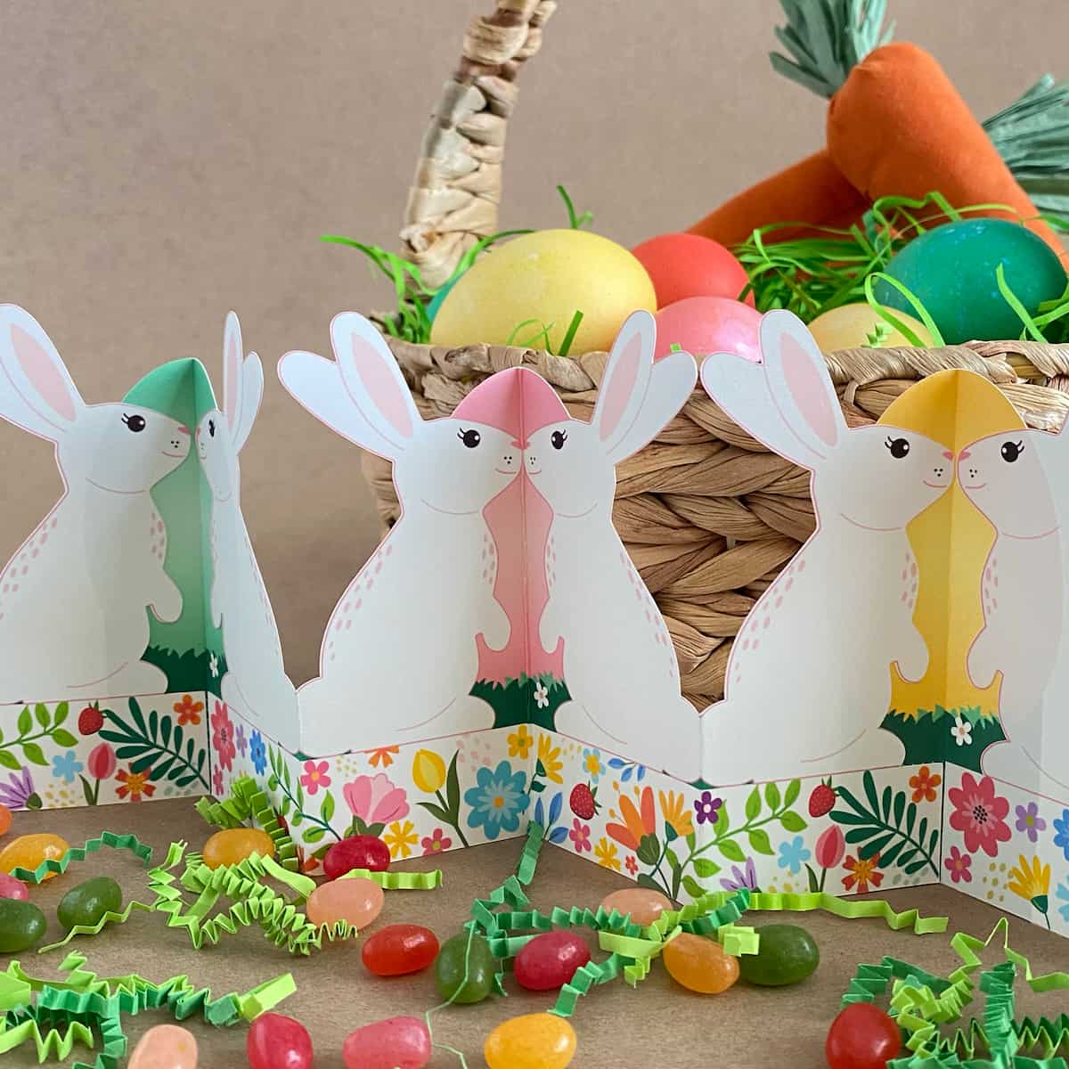 Finished printable standing bunny garland displayed on Easter table with basket, grass, colored eggs, and jelly beans – self-standing accordion fold tabletop decor