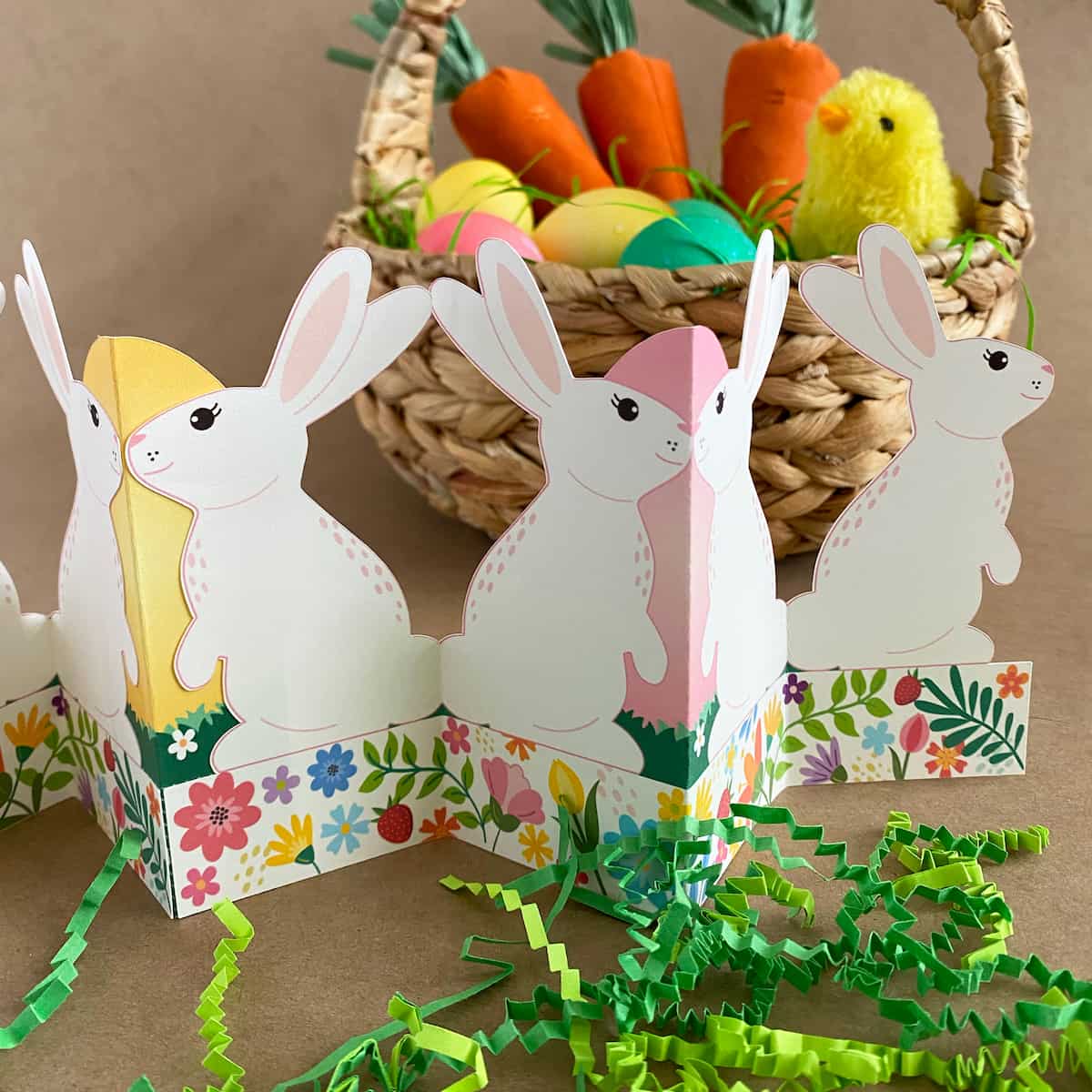 Finished printable standing bunny garland displayed on Easter table with basket, grass, colored eggs, and jelly beans – self-standing accordion fold tabletop decor
